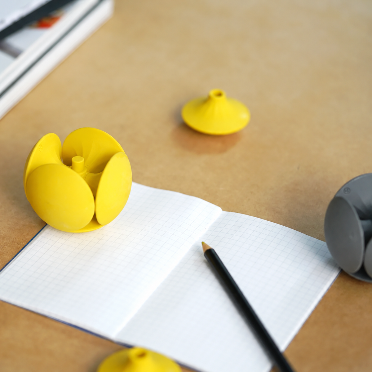 HMM Eraser Ball in Sunshine Yellow als Kartenhalter – eine Hand steckt eine Visitenkarte zwischen die gelben Radiergummi-Elemente.